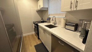 Una cocina compacta con lavavajillas, tostadora y lavabo.