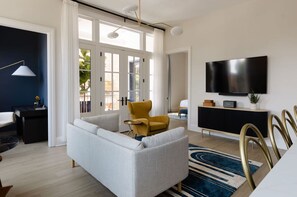 Un soggiorno moderno con un divano, una poltrona gialla, una TV a parete e un'area pranzo con tavolo e sedie.