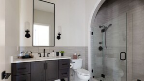 Une salle de bain moderne avec un meuble-lavabo en bois foncé, des toilettes blanches et une douche à parois de verre.