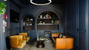 Une pièce avec un sol à carreaux, une table basse ronde, deux canapés et une bibliothèque.