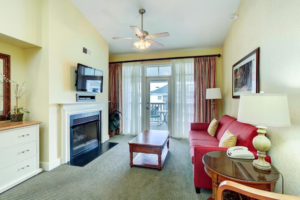 Una sala de estar con chimenea, televisión, sofá rojo y ventilador de techo.