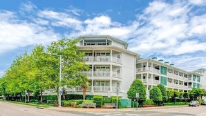 Un hotel de varios pisos con balcones, un césped verde y un cielo despejado.
