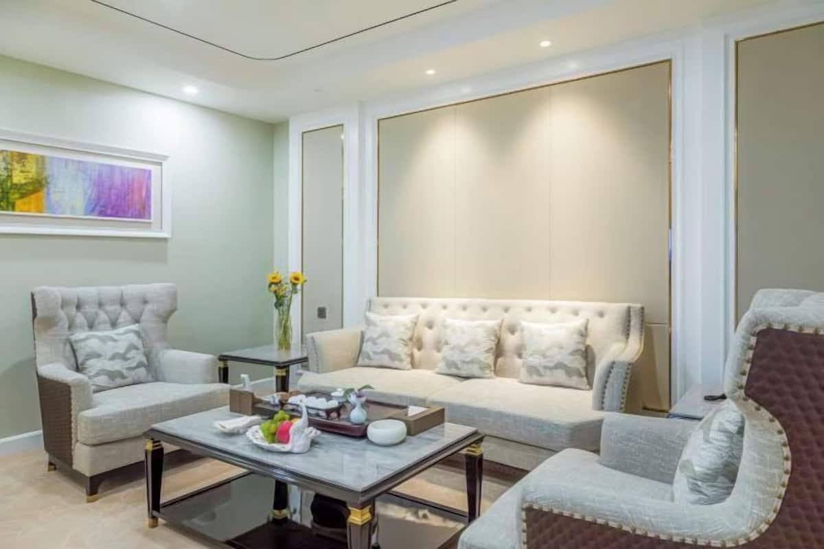 Una sala de estar moderna con un sofá, sillones, una mesa de centro y un cuadro en la pared.