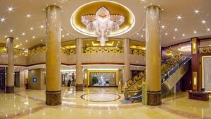 Un'ampia hall con un'area centrale circolare, grandi colonne e un imponente lampadario.