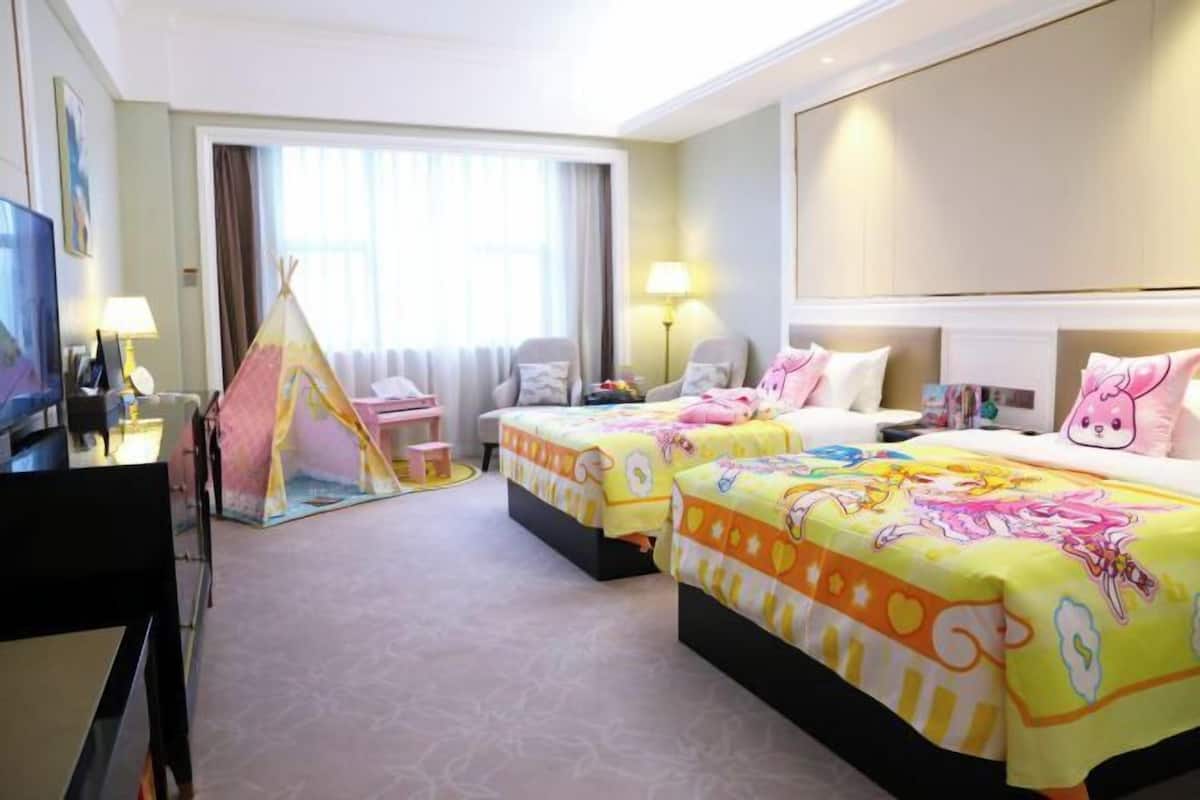 Habitación de hotel con dos camas, televisión, escritorio, silla, lámpara, ventana y una tienda de campaña.