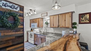 Una cocina con armarios de madera, encimera de granito y una isla también de madera.