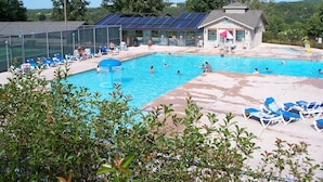 Una piscina con sillones de descanso y un edificio con paneles solares.