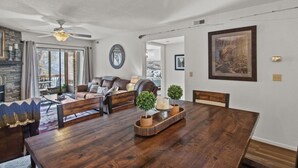 Amplia sala de estar con mesa de comedor de madera, sofás de cuero y chimenea de piedra.