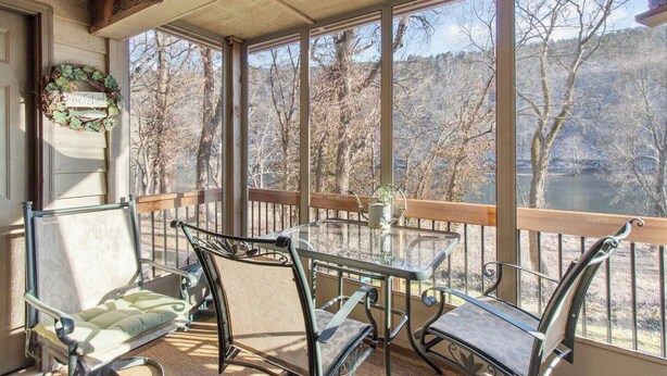 Un espace extérieur abrité, avec une table et des chaises, offrant une vue sur une rivière et des arbres.