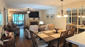 A dining area with a wooden table and chairs, a fireplace, and a television in the background.