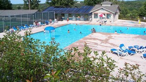 Una piscina con sillones de descanso y un edificio con paneles solares.