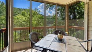 Un patio techado con mesa y sillas, con vista a un área boscosa.