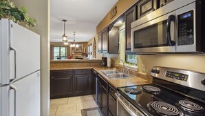 Una cocina moderna con electrodomésticos de acero inoxidable, armarios oscuros y una isla central.