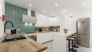 A modern kitchen with white cabinets, a stainless steel refrigerator, and a wooden countertop. - Surf & Chill Peniche Villa (Peniche)