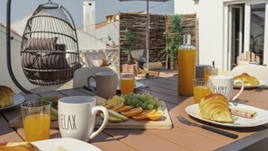 A breakfast table with croissants, fruit, and a beverage. - Surf & Chill Peniche Villa (Peniche)