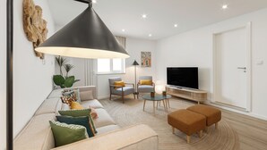 A modern living room with a sofa, armchairs, a coffee table, and a TV. - Surf & Chill Peniche Villa (Peniche)