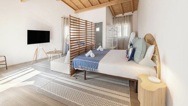 A modern bedroom with a large bed, a TV, a wooden ceiling, and a view of the outdoors. - Surf & Chill Peniche Villa (Peniche)
