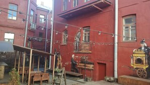 A courtyard with a red building, outdoor seating, and a mural of a man playing a piano. - City Hall apartment in 19th century house, heart of old town
 (Minsk)