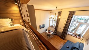 A cozy room with a bed, a sofa, a dining table with chairs, and a window with curtains. - City Hall apartment in 19th century house, heart of old town
 (Minsk)