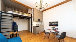 A compact living space with a bunk bed, kitchenette, dining area, and a blue sofa. - City Hall apartment in 19th century house, heart of old town
 (Minsk)