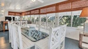 Une pièce lumineuse avec un ventilateur de plafond, des meubles blancs et de grandes fenêtres.