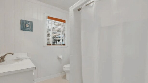 Une salle de bain avec un lavabo blanc, des toilettes et un rideau de douche.