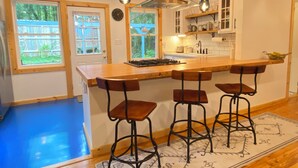 A kitchen with a wooden island, bar stools, and pendant lighting. - 3 Miles to Asheville! Sunfilled Cabin with Wi/Fi (Asheville)