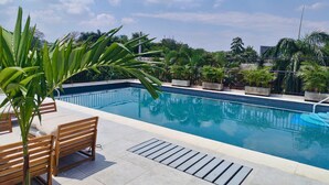 A swimming pool with a tiled deck, wooden benches, and potted plants. - Cali, Colombia. Loft en zona exclusiva Miro Living 809 (Cali)