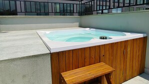 A wooden bench and a hot tub in front of a modern building with large windows. - Cali, Colombia. Loft en zona exclusiva Miro Living 809 (Cali)