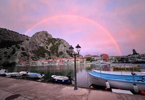 A harbor with boats docked, a mountain in the background, and a rainbow in the sky. - Omiš, charming 1-bedroom apartment near beach and center, with WiFi, AC, parking (Omiš)