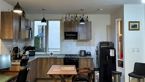 A modern kitchen with wooden cabinets, a dining table, chairs, a stove, a microwave, and a refrigerator. - Hermoso Departamento Completo, en Tlalnepantla (Tlalnepantla)