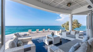 A covered outdoor seating area with a view of the sea, furnished with white sofas and chairs, and a pool in the center. - Isla Matamba (Rosario Islands)