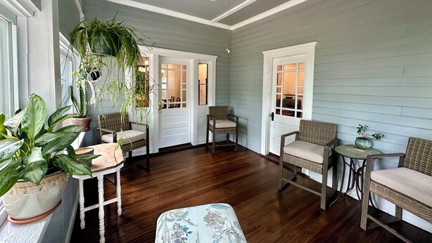 A room with wooden flooring, wicker furniture, and potted plants. - 1910 on Route 66 is a Charming historic 2 bedroom 2 bath home, close to downtown (Saint James)