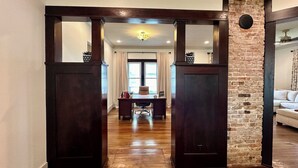 A hallway with a wooden door frame, a brick wall, and a dining area in the background. - 1910 on Route 66 is a Charming historic 2 bedroom 2 bath home, close to downtown (Saint James)
