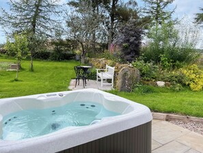 A hot tub in a garden with a lawn, a wooden deck, and outdoor furniture. - 1 bedroom accommodation in Glenisla, near Blairgowrie (Glenisla, near Blairgowrie)