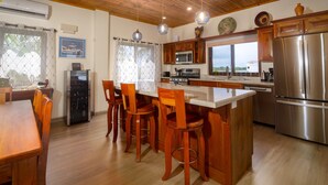 Een moderne keuken met houten kastjes, roestvrijstalen apparatuur en een centraal eiland met barstoelen.