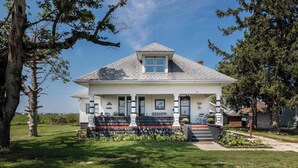 Une maison à deux étages avec un toit à pignon, un porche à l’avant avec un banc et un petit jardin.