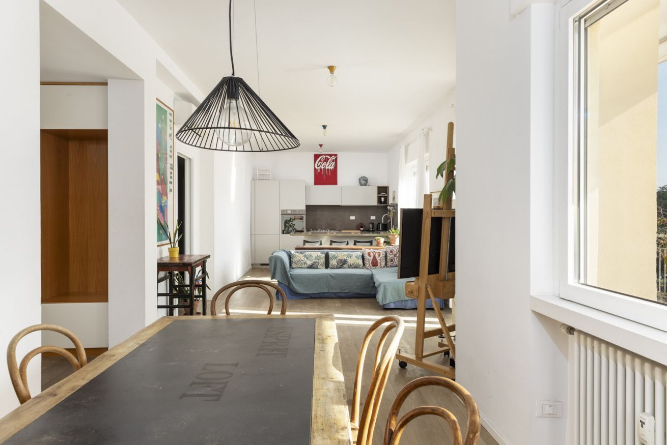A dining area with a black table, wooden chairs, and a hanging light fixture.