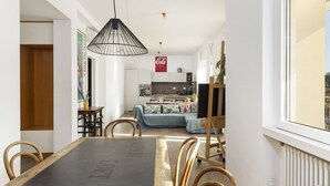 Een eetgedeelte met een zwarte tafel, houten stoelen en een hanglamp.