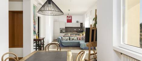 A dining area with a black table, wooden chairs, and a hanging light fixture.