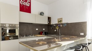Een moderne keuken met een groot kookeiland, barstoelen en een Coca-Cola bord.