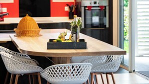 A modern kitchen with a red accent wall, a large island with stools, and a built-in oven.