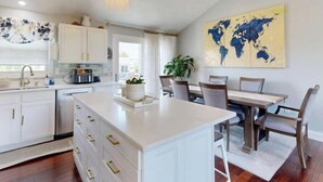Una cucina moderna con mobili bianchi, un'isola centrale e luci a sospensione.