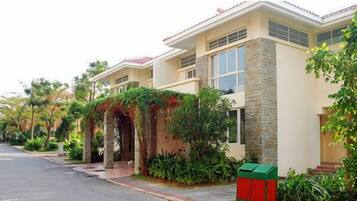 A row of modern houses with a stone facade, a red trash bin, and lush greenery.