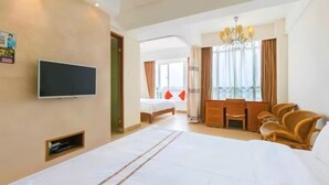 A hotel room with a large bed, a television, a desk with chairs, and a view of the outdoors. - Youjia Holiday Apartment Sanya Yalongwan Shenya Feicuigu (Sanya)