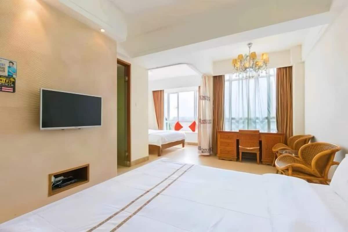 Une chambre d’hôtel avec un grand lit, une télévision, un bureau avec des chaises et une vue sur l’extérieur.