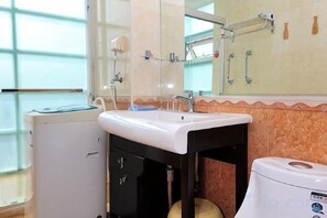 Un baño con lavamanos, espejo, toallero y retrete.