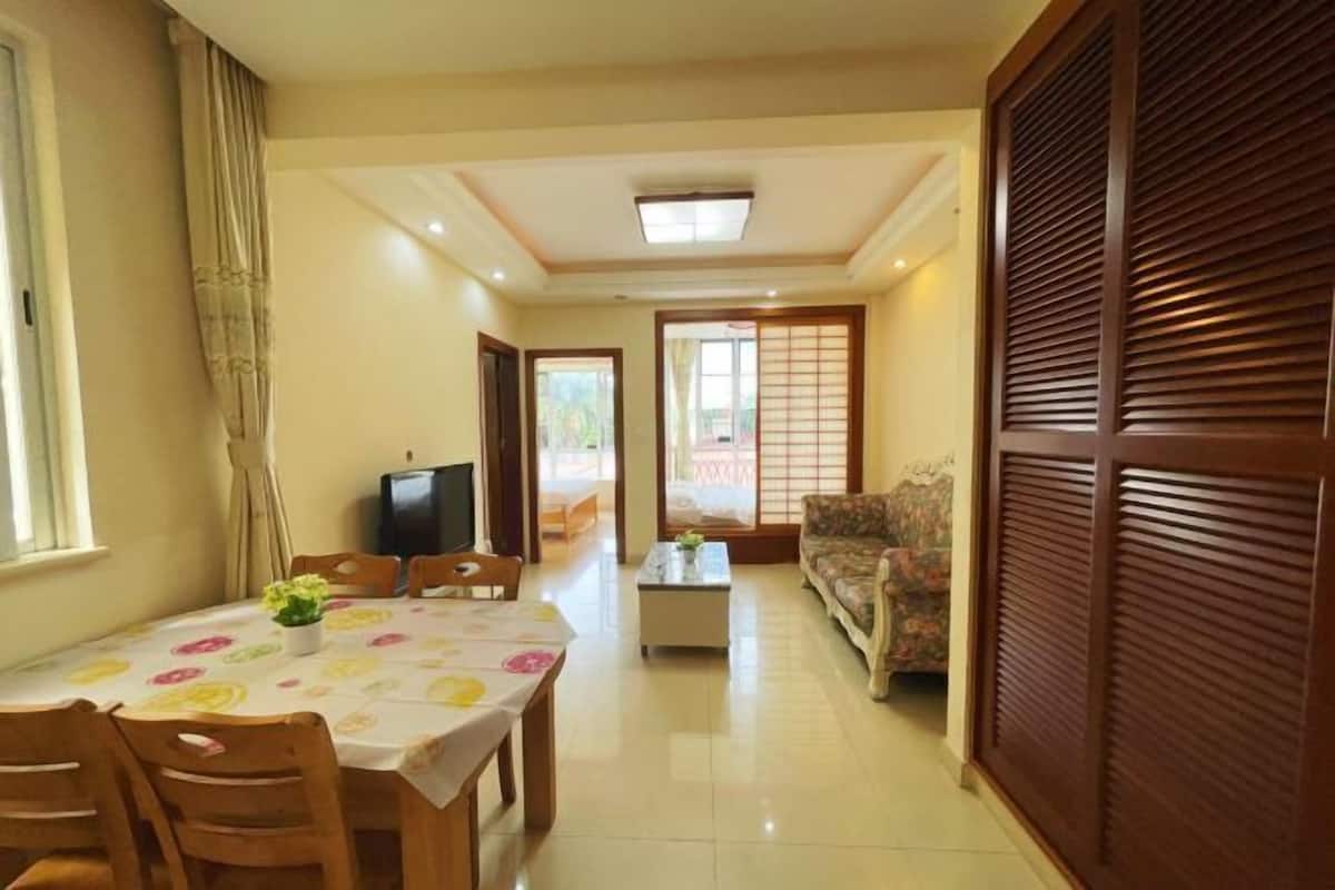 Un coin repas avec une table dressée pour quatre personnes, un canapé, un téléviseur et une porte coulissante.