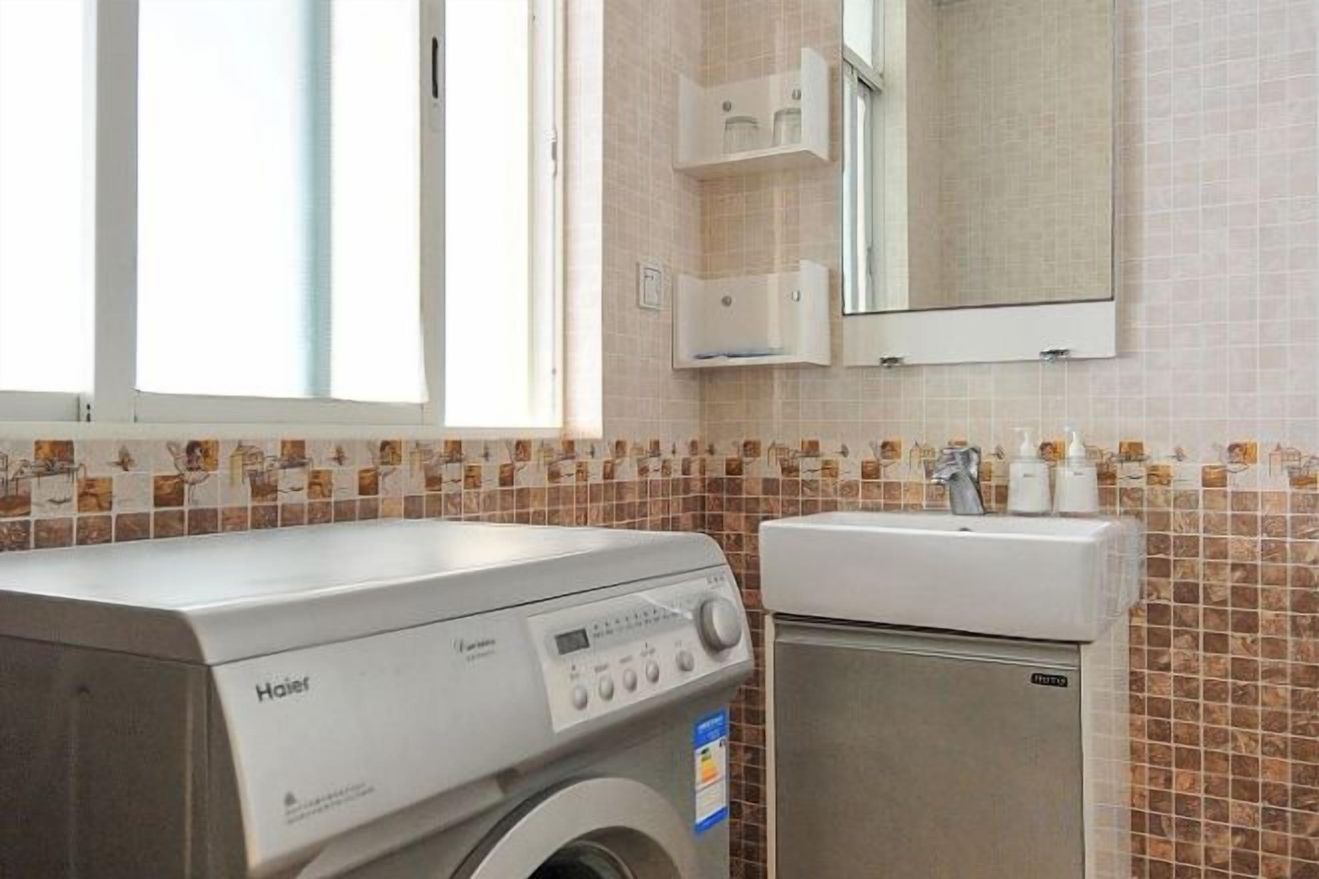 A laundry room with a front-loading washer and dryer, a sink, and a mirror above the sink.