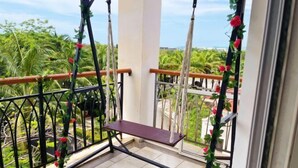 A balcony with a wooden bench, metal railings, and a view of greenery and buildings. - Youjia Holiday Apartment Sanya Yalongwan Shenya Feicuigu (Sanya)
